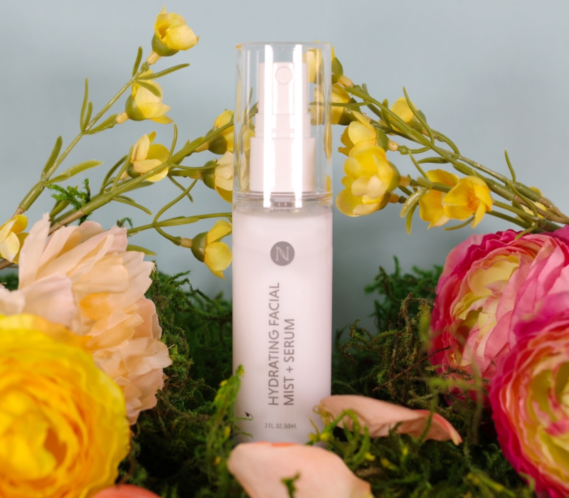 Neora's Hydrating Facial Mist sitting in a bed of spring flowers.